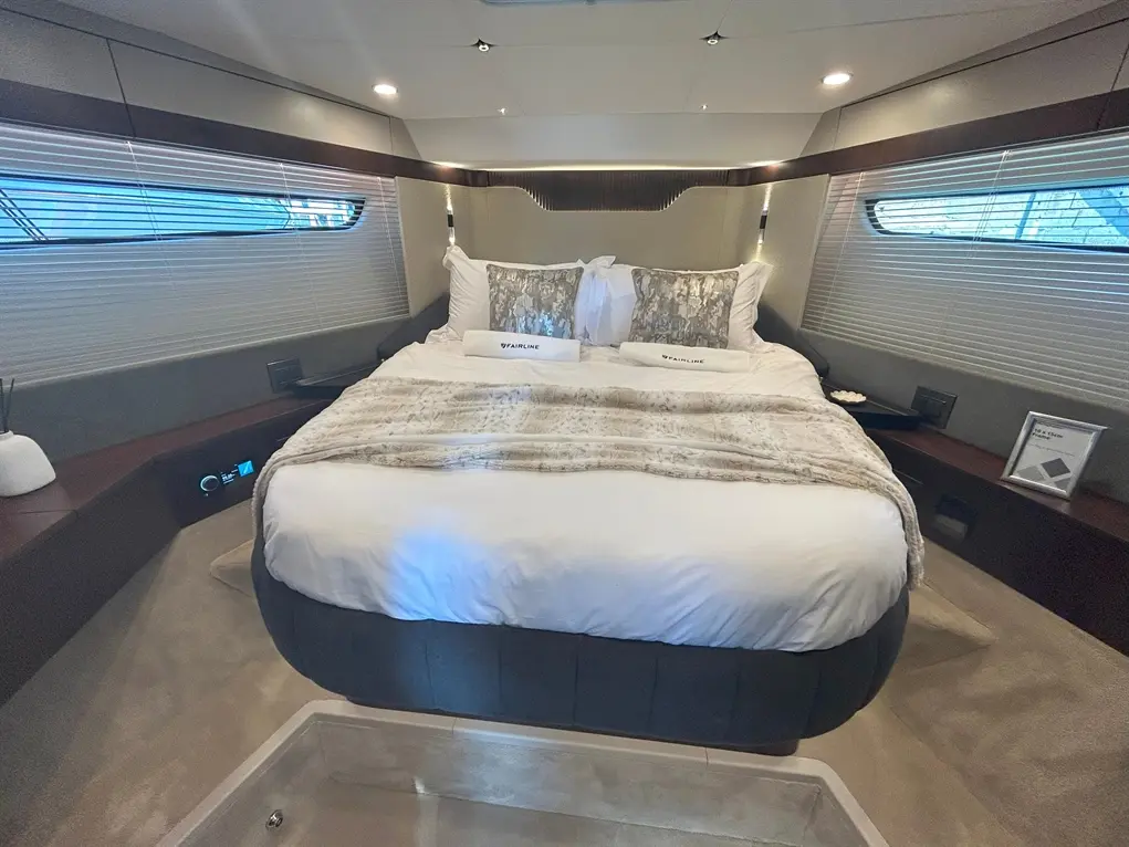 Luxurious yacht bedroom featuring a king-size bed with decorative pillows, soft blanket, and ambient lighting.